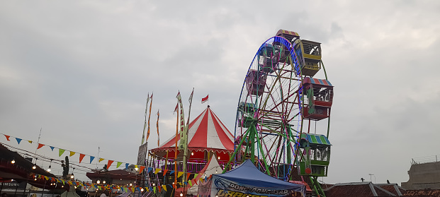 Blora, Indonesia - Dec 24, 2022: Local amusement fun fair with Ferris wheels at the night market.