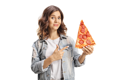 Young woman holding a yummy pepperoni pizza slice and pointing isolated on white background