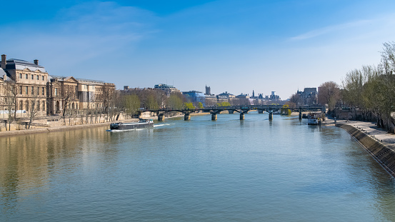 Paris, the Pont des Arts on the Seine, beautiful panorama with houseboat, and the Saint-Jacques tower in background