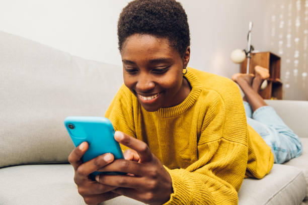 African woman using cellphone at home stock photo