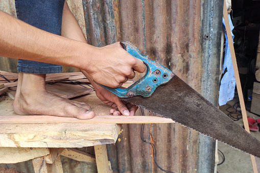 A carpenter working manually with a hand saw on a wooden background