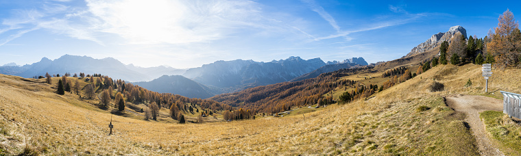Panoramic view of an alpine mountian landscape in the Dolomites with autumn colors and blue sky
