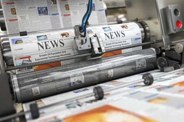 Photo of Newspaper or hournal with news printing on a printing machine in a typography.