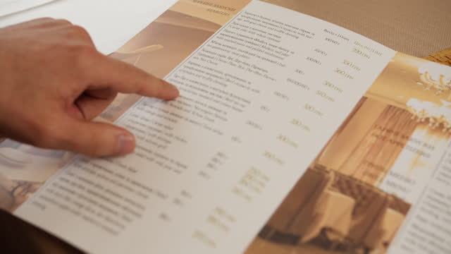 Close-up finger guides through the menu list in hotel restaurant or ordering food from the menu