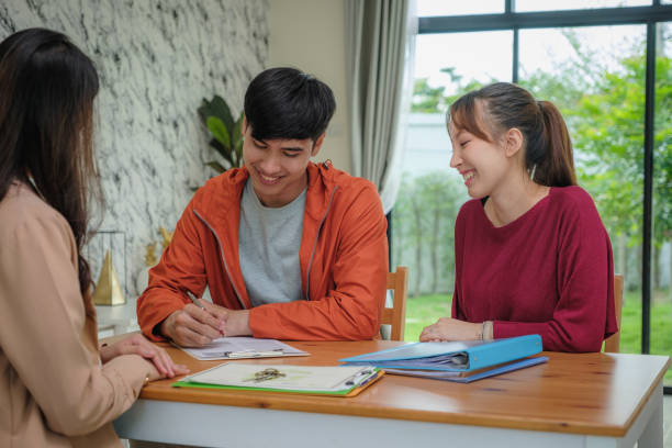 Young Asian couple negotiating signing a contract on meeting with real estate agent or landlord Young Asian couple negotiating signing a contract on meeting with real estate agent or landlord, Loan and mortgage, Homeowners and New home concept, buy or sale and moving home, first property purchase BEING HAPPY stock pictures, royalty-free photos & images