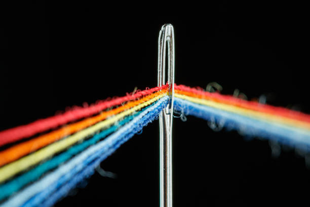 istock multi-colored threads for sewing in the form of a rainbow pass through an antique needle on a black background 1455034455