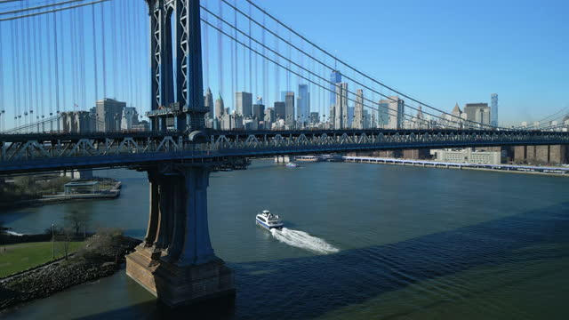 Slide and pan footage of double deck steel bridge over river. Manhattan skyscrapers in background. New York City, USA