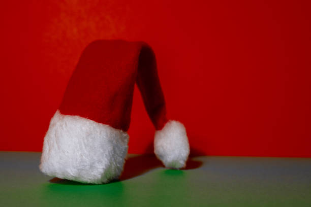 istock Santa hat on isometric green red background. Copy space for your text. Mock up for advertisement. Holiday Christmas composition. Minimalistic greeting card 1455041746