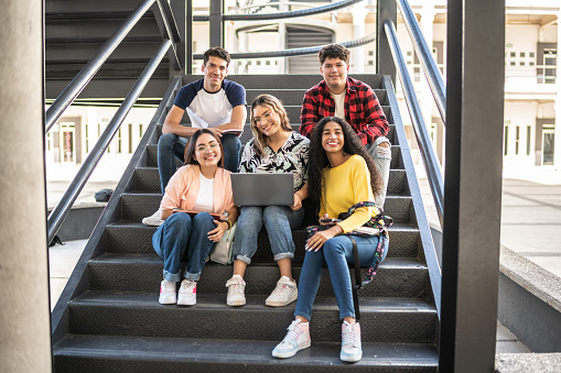 Portrait of young friends together on university stairs