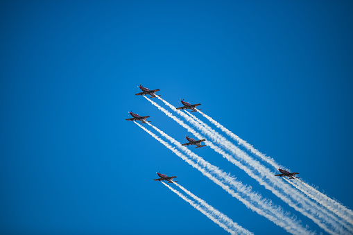 A group of airplanes soaring high in the clear blue sky, leaving a sharp white trail of smoke behind them