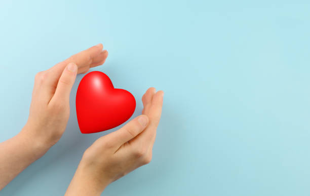 istock Red heart in woman hands on blue background. Copy space 1455043990