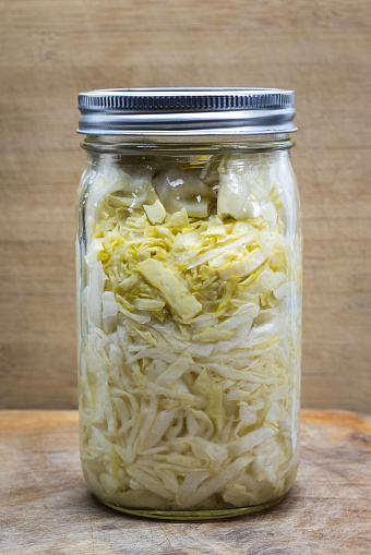 Home made fermented cabbage in a wide mouth jar on a wooden background