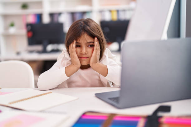 istock Adorable hispanic girl student using laptop with worried expression at classroom 1455045872