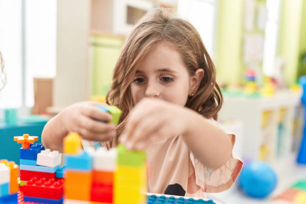 istock Adorable hispanic girl playing with construction blocks sitting on table at kindergarten 1455047388