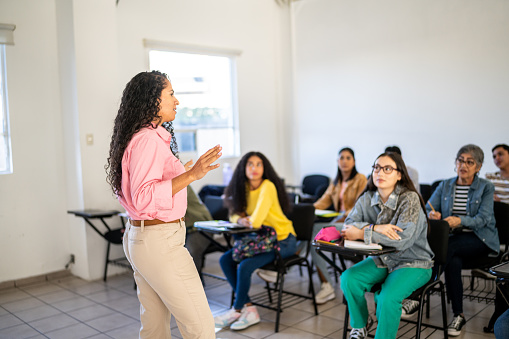 Mid adult teacher explaining lesson to university students in the classroom at university