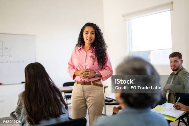 Mid Adult Teacher Answering Questions From University Students In The Classroom At University Stock Photo - Download Image Now