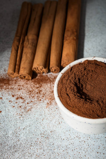 istock Ceylon cinnamon sticks and ground cinnamon bowl. Carelessly scattered cinnamon on the background. 1455049779