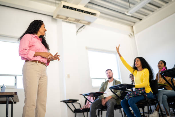istock Young woman making asking a question to teacher in the classroom at university 1455051402