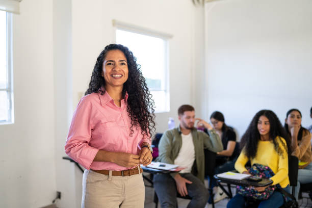 Portrait of a mid adult teacher in the classroom at university Portrait of a mid adult teacher in the classroom at university lecturer stock pictures, royalty-free photos & images