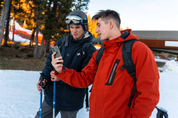 two boys in ski clothes looking at the phone - apres ski winter friendship ski imagens e fotografias de stock