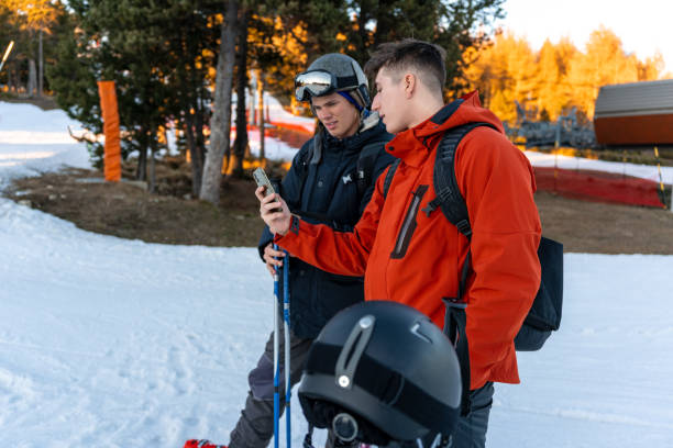 two boys in ski clothes looking at the phone - apres ski winter friendship ski imagens e fotografias de stock