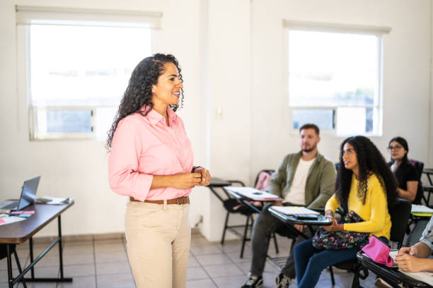 istock Mid adult teacher explaining lesson to her students in the classroom at university 1455053343