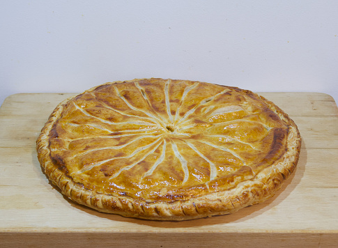Homemade french Traditional Galette des Rois, or kings cake on a wooden board.