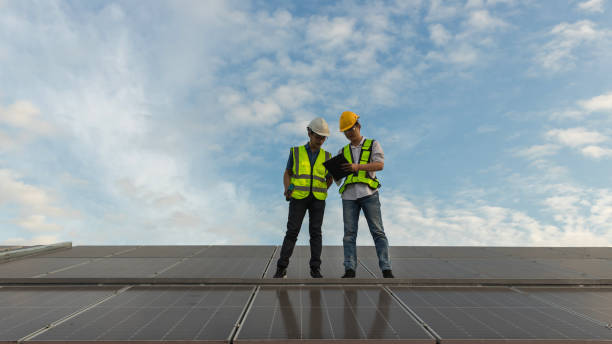 istock Engineer working setup Solar panel at the roof top. Engineer or worker work on solar panels or solar cells on the roof of business building 1455064886
