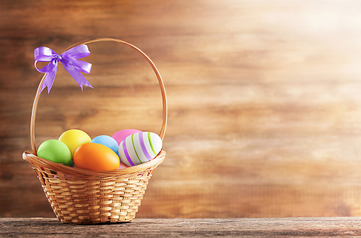 in the basket there are colorful Easter eggs on a wooden background with a place for text