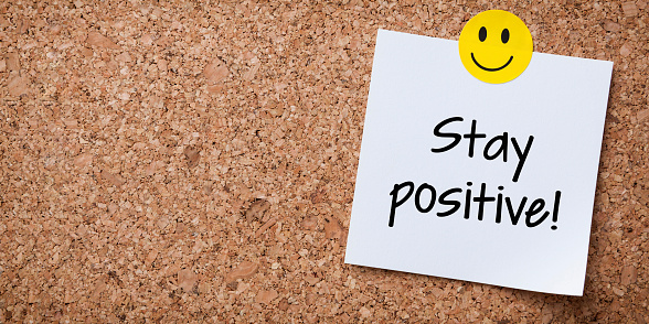 White Sticky Note With Stay Positive And Red Push Pin On Cork Board
