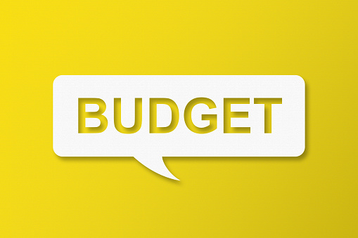 Budget and Speech Bubbles with Copy Space On Yellow Cardboard Background
