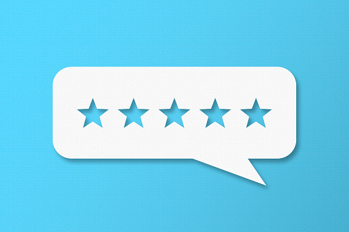 Feedback Concept - White Chat Bubble With Cut Out Star Shapes On Blue Cardboard Background