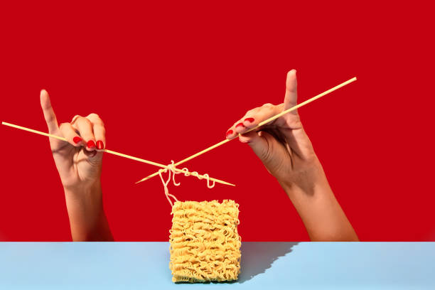 creative image with female hands knitting instant noodles on blue table over vivid red background. dinner. food pop art photography. - eating senior adult color image spaghetti imagens e fotografias de stock