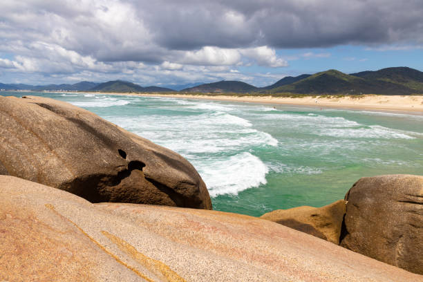 Rocks and waves at Joaquina beach Rocks and waves at Joaquina beach, Florianopolis, Santa Catarina, Brazil joaquina beach in florianopolis santa catarina brazil stock pictures, royalty-free photos & images