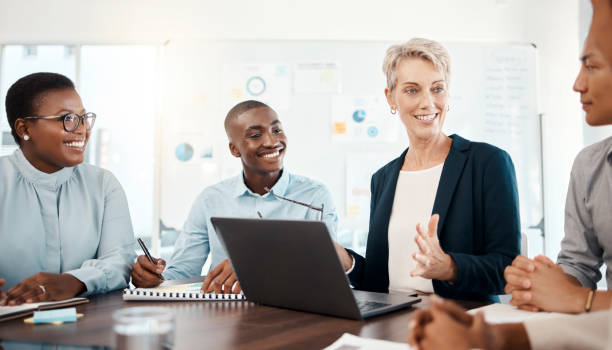 istock Diversity, laptop and team brainstorming, conversation and planning for group project with leader, smile and in office together. Teamwork, talking or discussion for marketing strategy or sales growth 1455074390