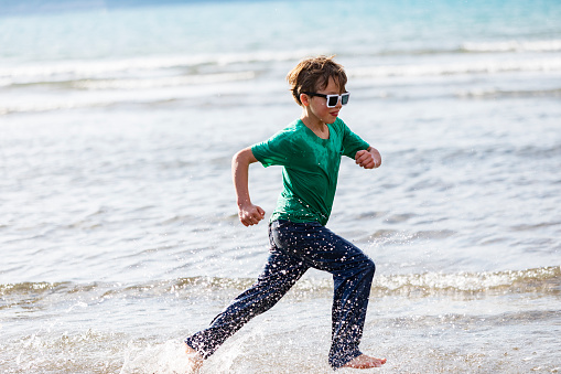 Pre-teens boy running in water at the beach