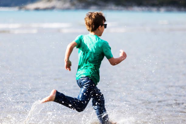 istock Pre-teens boy running in water at the beach 1455075201