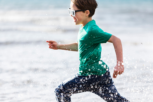 Pre-teens boy running in water at the beach