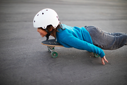 Pre-teens Korean boy riding on skateboard in park in crash helmet