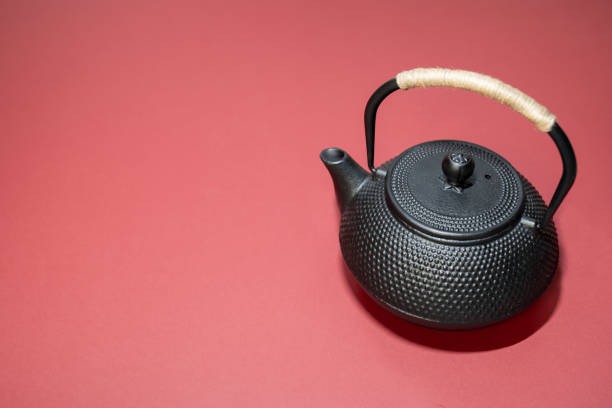 istock black metal tea kettle with handle, asian teapot on red background, copy space, place for text, tea ceremony, chinese new year 1455078898