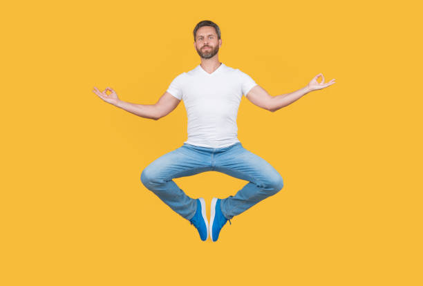 istock man having levitating meditation isolated on yellow background. meditation guy with mudra gesture. 1455079326