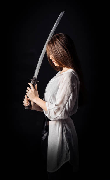 istock Young asian woman with katana sword. Side view. Vertical studio photography. 1455081977