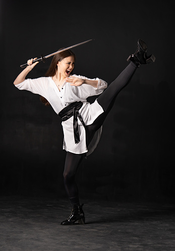 Aggressive asian woman with katana sword attack. Self defense and attack concept. Vertical photography.