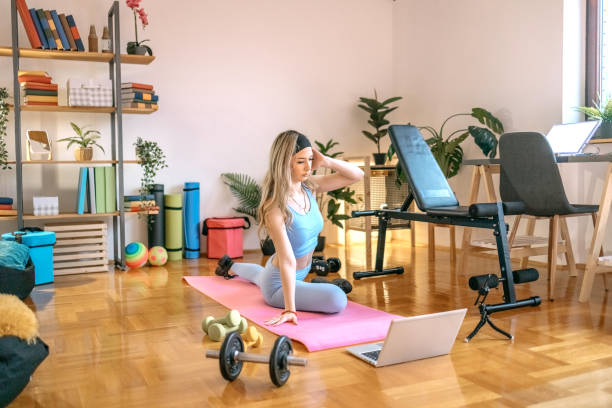 istock Young woman exercising at home using laptop 1455082146