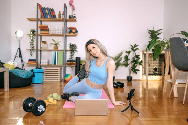 istock Young woman exercising at home using laptop 1455082264