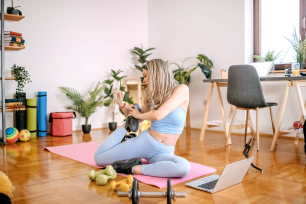 istock Young woman exercising at home using laptop 1455082353