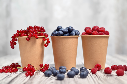 Blueberries, red currants, raspberries. Light wooden background. Shallow depth of field.