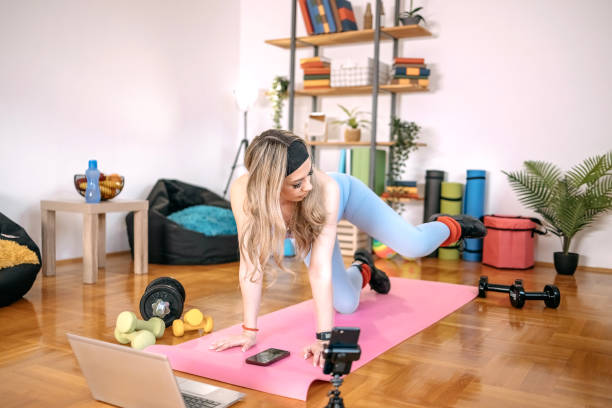 istock Young woman exercising at home using laptop 1455083606