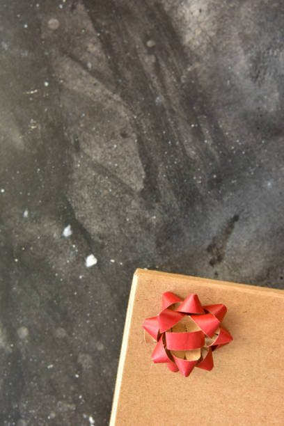 Gift  box on a  black background, decorated with a textured bow and feathers,creating a romantic atmosphere for anniversary presents,valentine and birthday gift, post cards. Top view,copy space