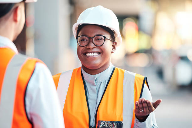 Engineer, happy or consulting with architect on building strategy, planning and schedule on industrial site. Black woman in conversation with employee, staff or manager about architecture development